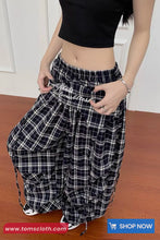 Person wearing black and white checkered pants with text on a wooden floor.