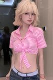 Person wearing a pink checkered crop top and blue jeans indoors.