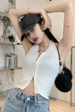 Woman wearing a white top and blue jeans with a black cap indoors.