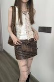Person wearing a white top and brown skirt with a matching handbag indoors.