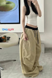 Person wearing a white top and beige pants in front of a screen displaying 'TOMS CLOTH'.