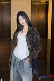 Woman in a leopard print jacket and white top standing in an elevator shaft.