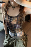 Person wearing a plaid tank top and green pants indoors.