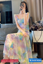 Woman in a colorful dress taking a mirror selfie in a living room.