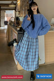 Person wearing a blue sweater and plaid skirt in a kitchen setting with 'TomsCloth' branding.
