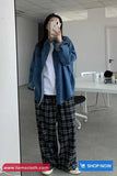 Person wearing a blue jacket and plaid pants taking a mirror selfie in an office setting.