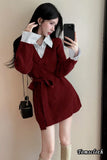 Woman taking a mirror selfie wearing a red coat and white shirt, holding a black handbag.