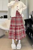 Person wearing a white cardigan and red plaid skirt indoors.