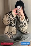 Person wearing a patterned sweater taking a mirror selfie.