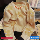 Beige sweater with floral embellishments on a table