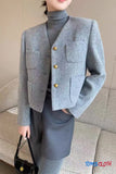 Person wearing a gray blazer with gold buttons indoors