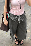 Person wearing a pink top and gray wide-leg pants on a stone pavement.