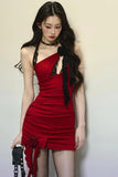 Woman wearing a red dress with black floral details against a plain background