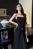 Woman in a black dress standing in an indoor setting with decor elements.
