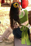 Woman in a green bikini with floral hair accessories sitting on sand