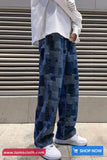 Person wearing blue patterned pants and white sneakers in front of a metallic shutter.