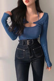 Person wearing a blue long-sleeve top and black high-waisted jeans against a plain background