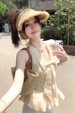 Woman taking a selfie outdoors wearing a beige hat and dress.