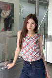 Woman wearing a plaid top and blue jeans standing indoors.