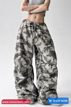 Camouflage pants worn by a person on a white background with 'TomsCloth' branding.