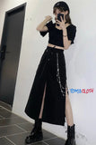 Person wearing a black outfit with a long skirt and platform shoes, taking a mirror selfie.