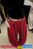Person wearing red pants with gold chains and a black top in an indoor setting.