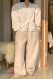 Person wearing a white jacket and beige fuzzy pants in a room with wooden flooring.