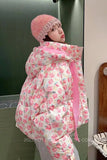 Person wearing a floral puffer jacket and pink hat indoors.