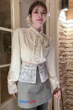 Person wearing a cream blouse with lace details in an indoor setting.