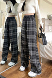 Person wearing a white sweater and plaid pants standing in a room.