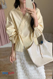 Person wearing a light yellow blouse and white skirt, holding a beige tote bag.
