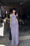 Woman in a long light purple dress standing outdoors with a rustic background