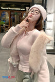 Person wearing a pink outfit with fur trim in an urban setting