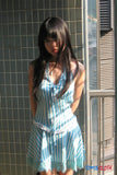 Woman in a blue and white striped dress standing against a tiled wall.