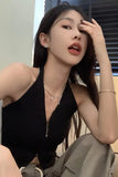 Woman wearing a black sleeveless top sitting indoors.