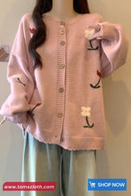 Pink cardigan with embroidered designs on a plain background