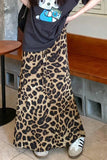 Person wearing a black t-shirt with a graphic design and a leopard print skirt in an indoor setting.