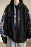 Person wearing a black hoodie with floral arm patches and a backpack.