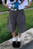 Person wearing a white t-shirt with a graphic design and dark shorts on a grassy background