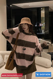 Woman wearing a striped sweater and bucket hat in an indoor setting with a 'Shop Now' call to action at the bottom.