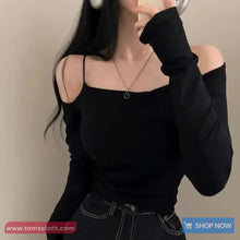 Person wearing a black long-sleeve top with cut-out shoulders against a neutral background.