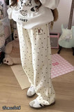 Person wearing a white hoodie with cartoon designs and polka dot pants in a room.