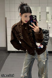 Person taking a mirror selfie wearing a brown jacket and ripped jeans in a tiled bathroom.