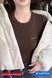 Person wearing a brown sweater with 'AMOUR' text, white cardigan, and jeans.