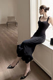 Woman in a black dress sitting by a window in a minimalistic room.