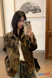 Person wearing a leopard print jacket in an indoor setting, taking a mirror selfie.