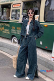 Woman in denim outfit standing in front of a vintage green bus, with 'Tom & Cloth' branding visible.