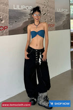 Person wearing a blue top and black pants in front of a LILIPOP branded backdrop.