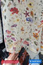 Floral patterned fabric held by a hand with a visible brand logo.