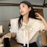 Woman wearing a white blouse with lace details in an indoor setting